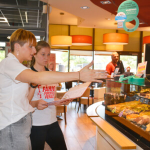 Saskia Oppl, Ausbildungsleiterin für Sachsen-Anhalt, Sachsen und Thüringen bei der Bäckerei Steinecke, erklärt Fenja Engel, worauf bei der Auslage der Backwaren geachtet wird.