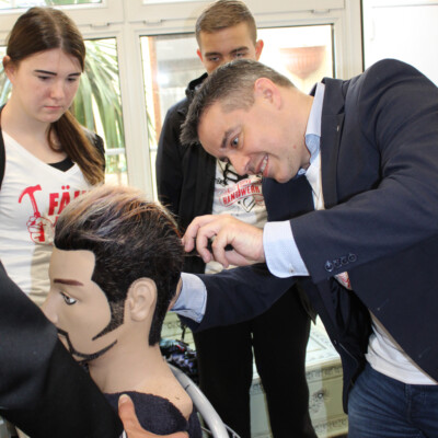 Landtagsabgeordneter Stefan Ruland probiert sich als Friseur. Friseurmeister Detlef Müller: „Herr Ruland macht das schon sehr gut.“